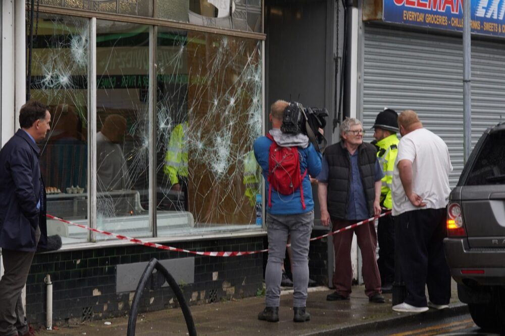 Police officers outside a damaged butchers shop on Murray Street in Hartlepool following an evening of unrest Credit: Owen Humphreys/PA