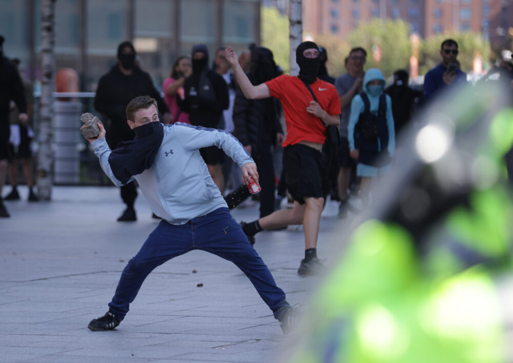 A man throws a brick during a protest in Liverpool, following the stabbing attacks on Monday in Southport, in which three young children were killed. Credit: PA