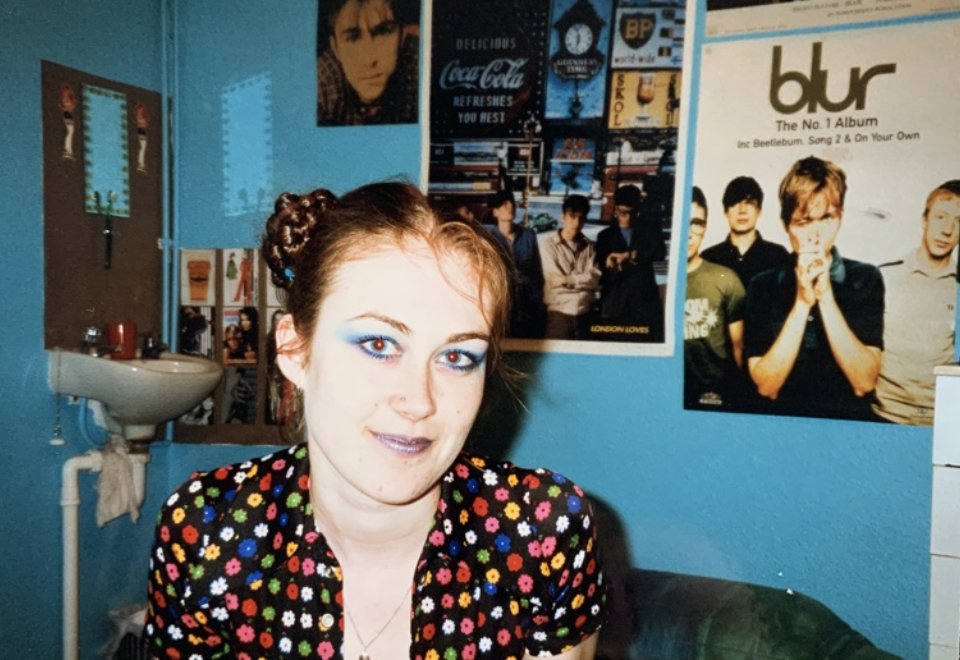 Liverpool student with blue eye shadow poses for photo in dorm room, Liverpool, UK, 1999/2000